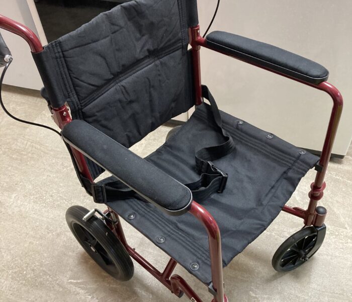 A red transport wheelchair with black upholstery