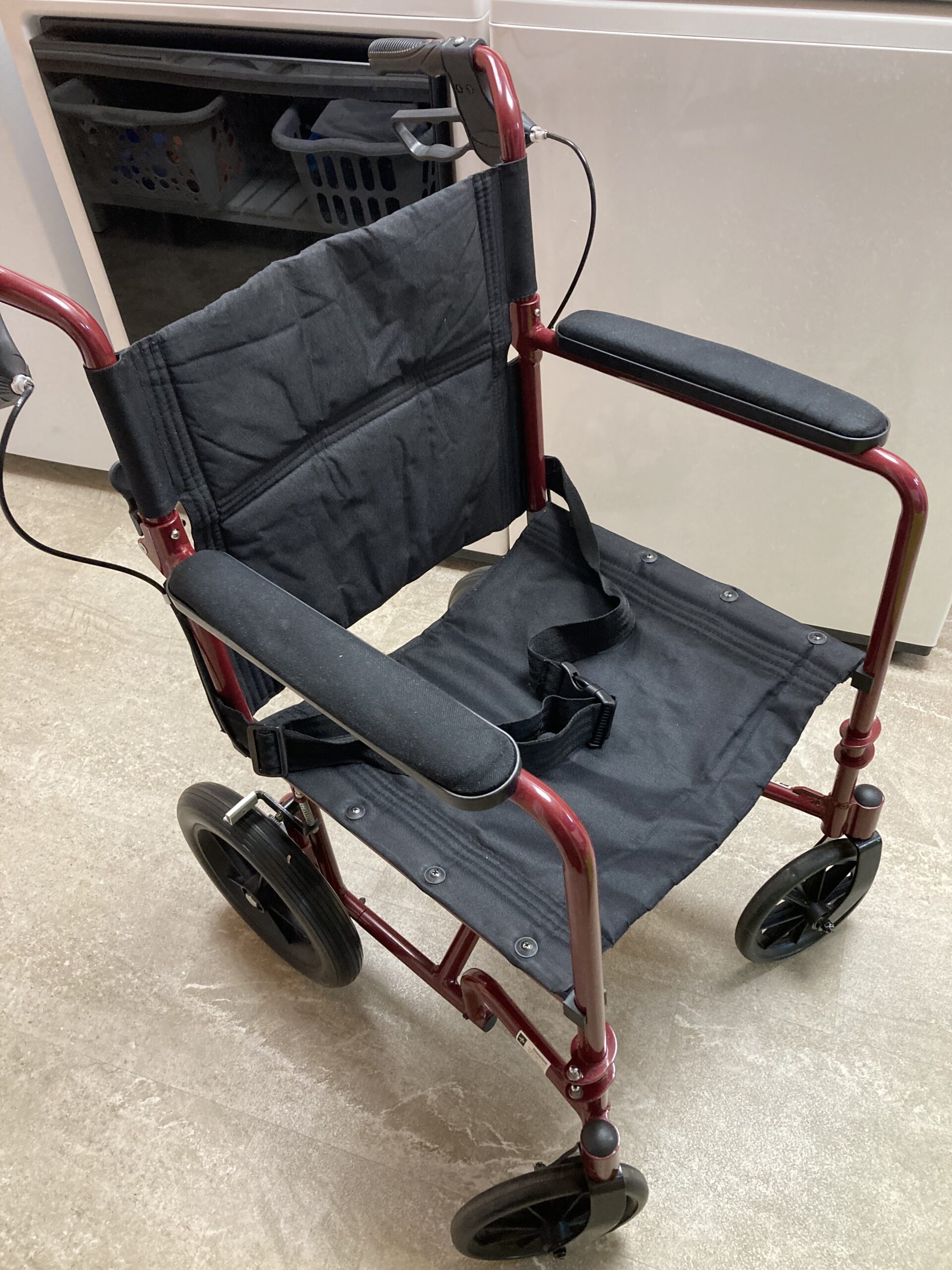 A red transport wheelchair with black upholstery