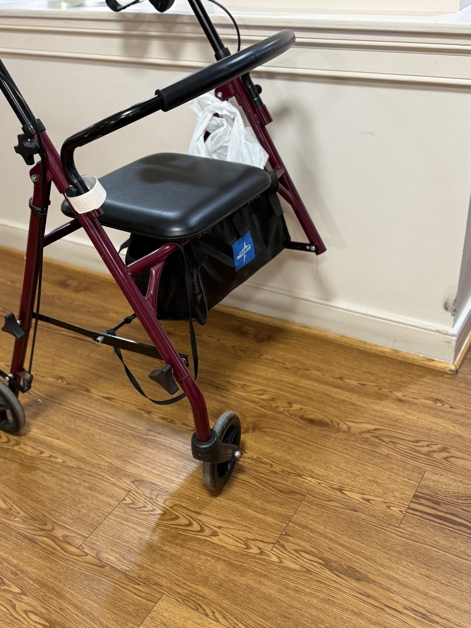 Burgundy Medline rollator with a missing right front leg.